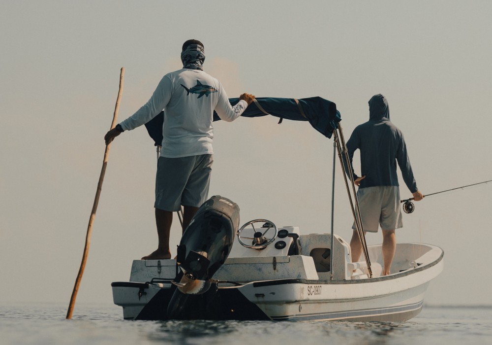 Marlon Leslie poling his skiff with an angler on the bow