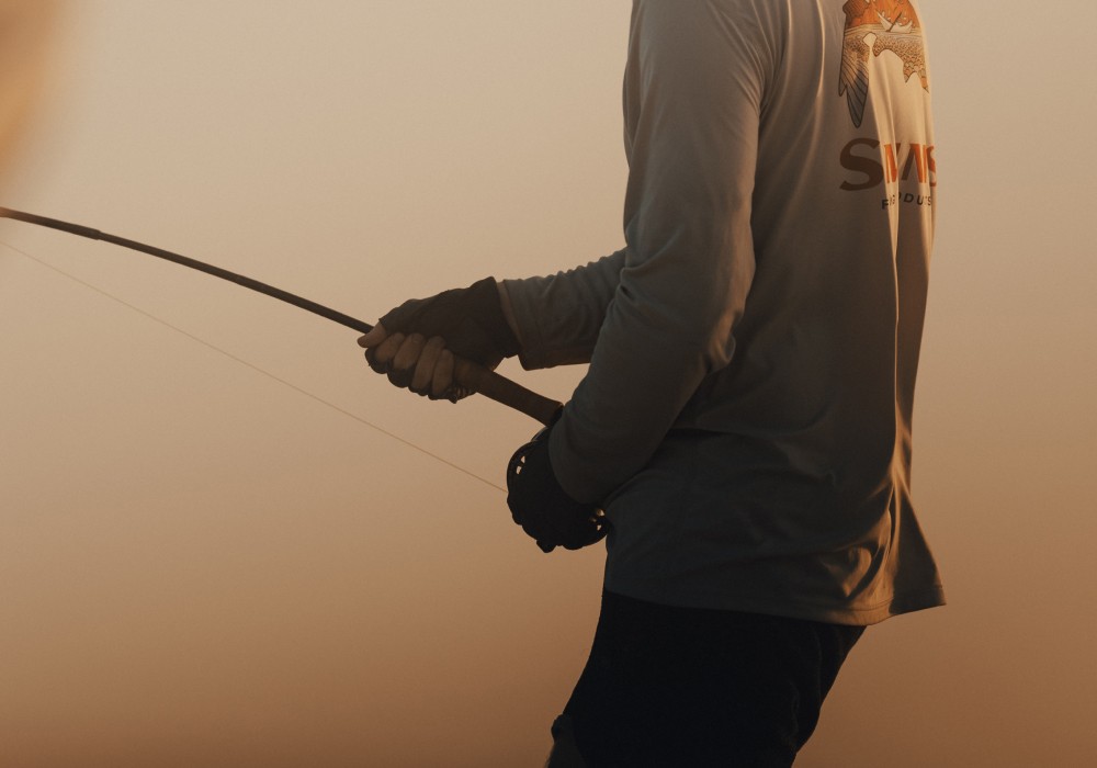 Angler holding a bent fly fishing rod during dusk